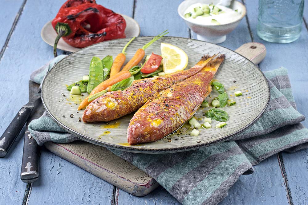 Rote Meerbarben mit Pesto, Gemüse und Zitrone serviert