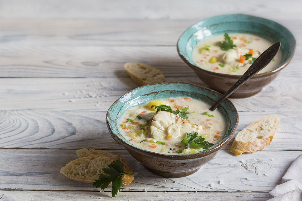 Steinbeisserfilet als Fischsuppe mit Petersilie und Baguette